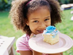 Portrait of a young girl holding a slice of cake