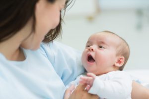 Mother holding a baby while he opens his mouth