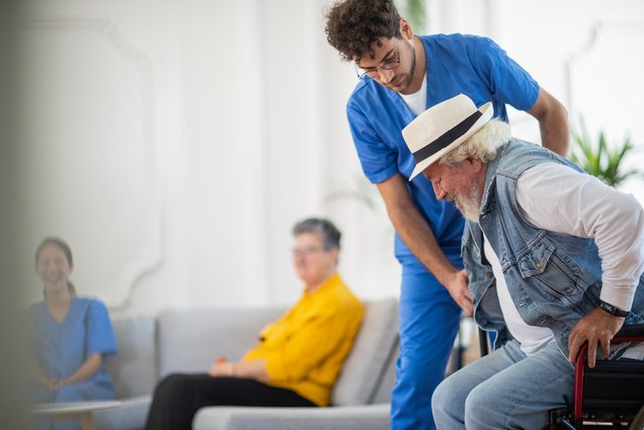 Fully Trained Hospice Staff – Flushing Hospital Male nurse helping an elderly man walk in a care setting