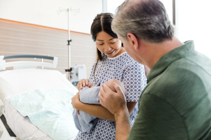 Mother and father admire their new baby The two parents admire their new baby that was born earlier that day.